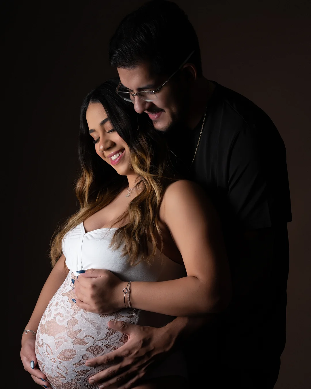Casal abraçado, renda branca sobre a barriga