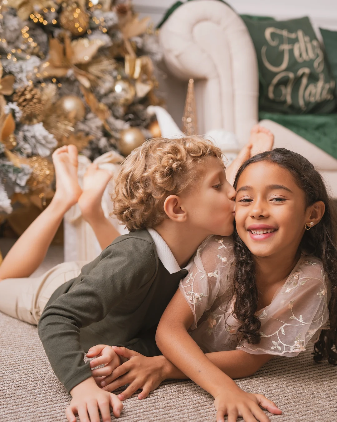 Irmãos deitados no tapete, um beijando o rosto do outro