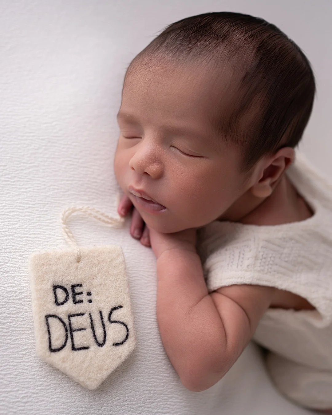 Recém-nascido dormindo ao lado de etiqueta 'De: Deus'