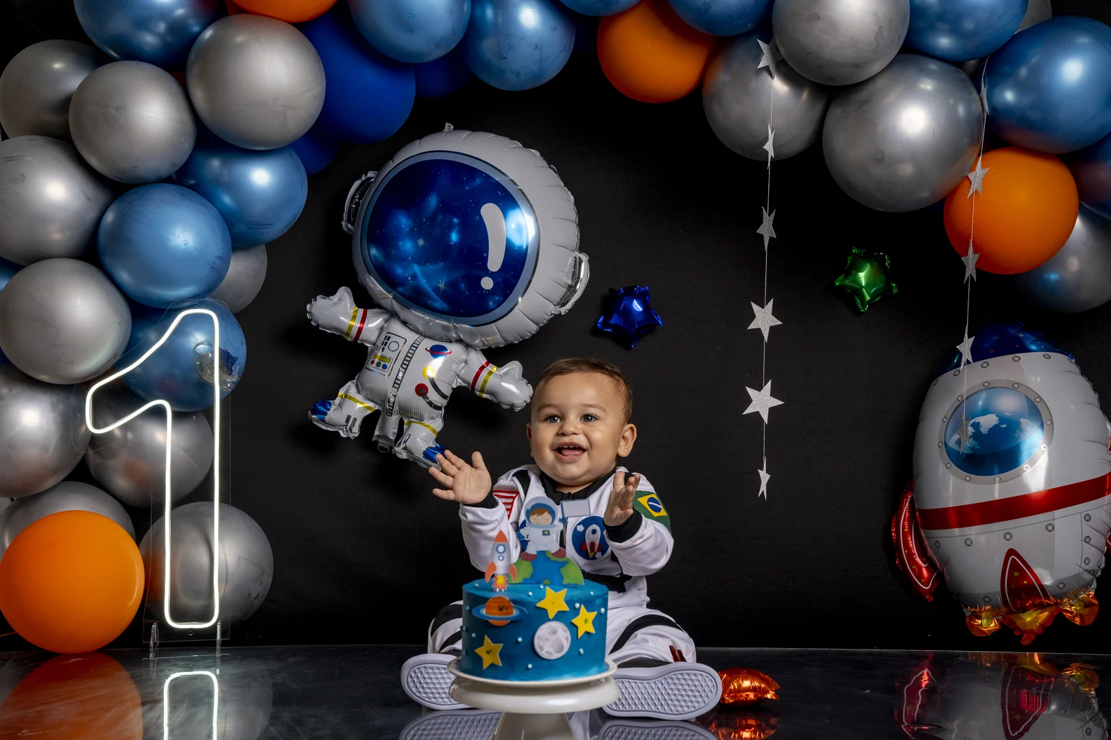 Bebê fantasiado de astronauta, batendo palmas com o bolo