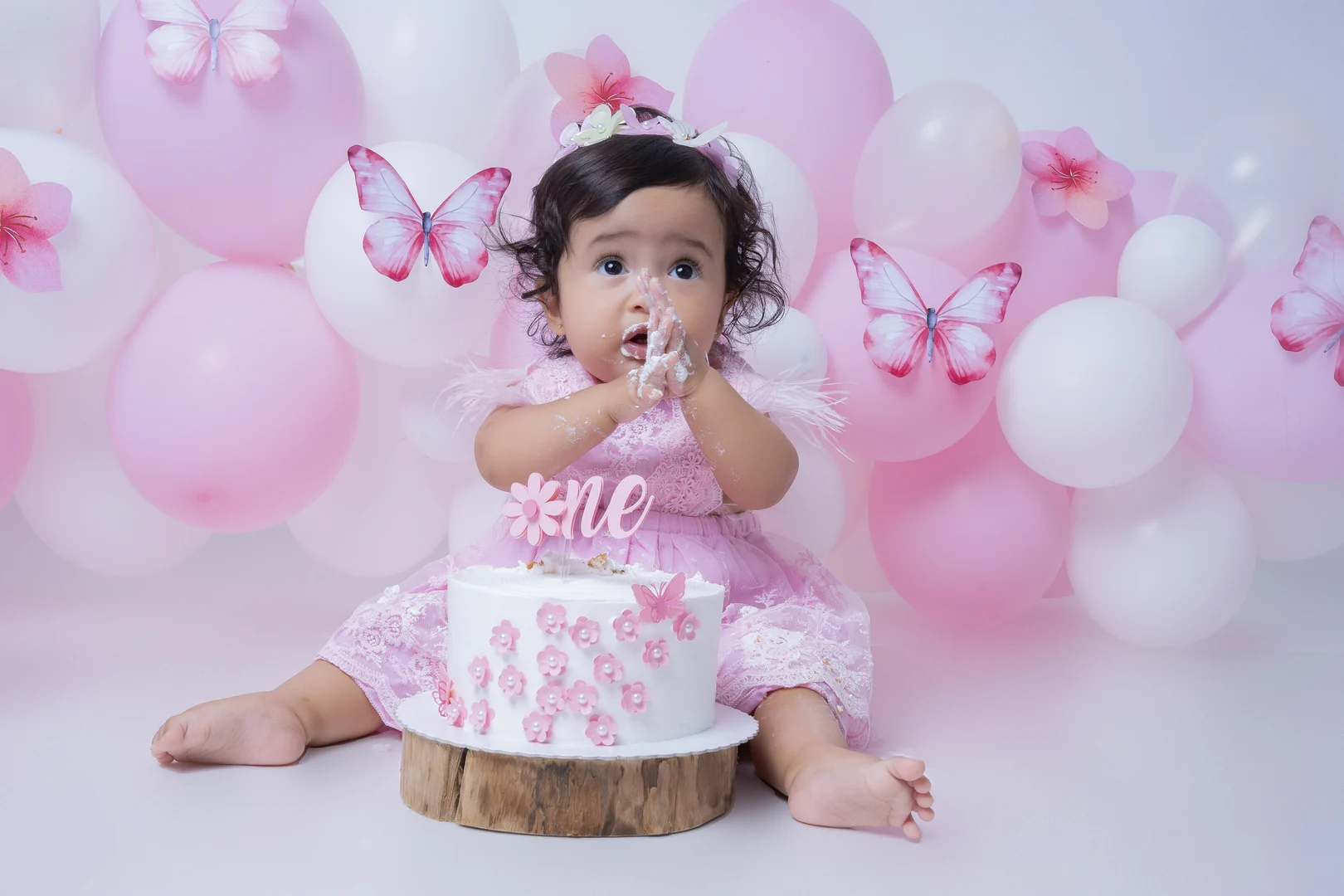 Bebê com o rosto sujo de bolo, tema borboletas rosa