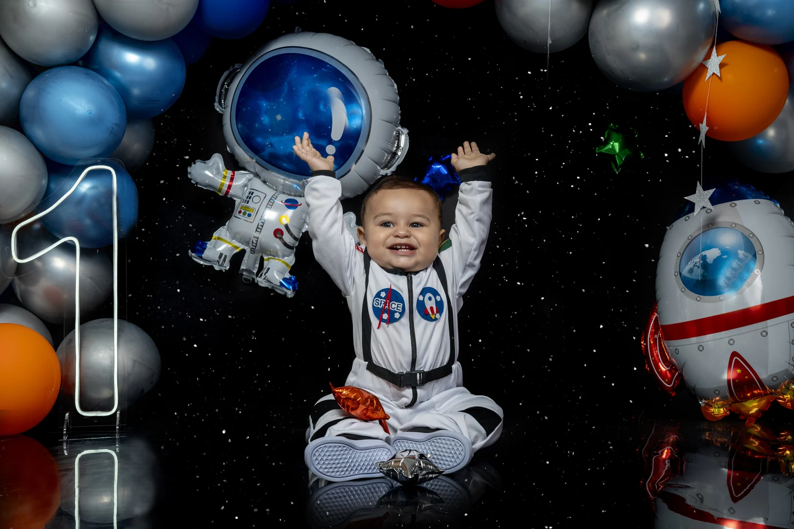 Bebê fantasiado de astronauta com os braços erguidos